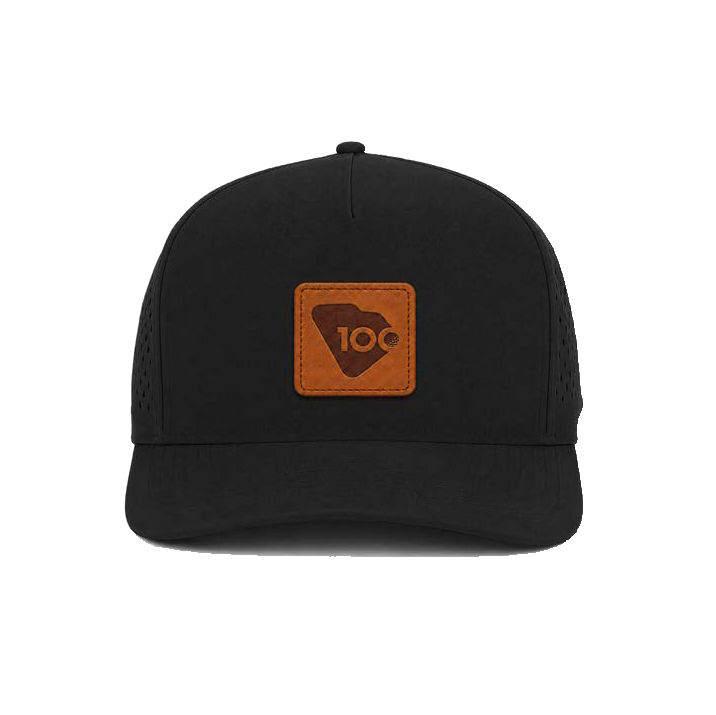 A black structured trucker-style cap with a brown rectangular leather patch on the front.