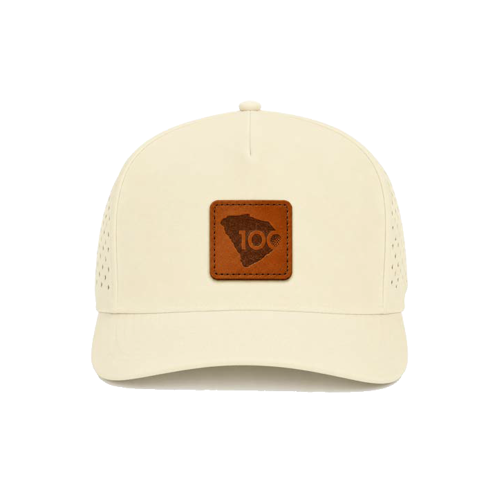 An off-white structured trucker cap with a brown leather patch on the front.