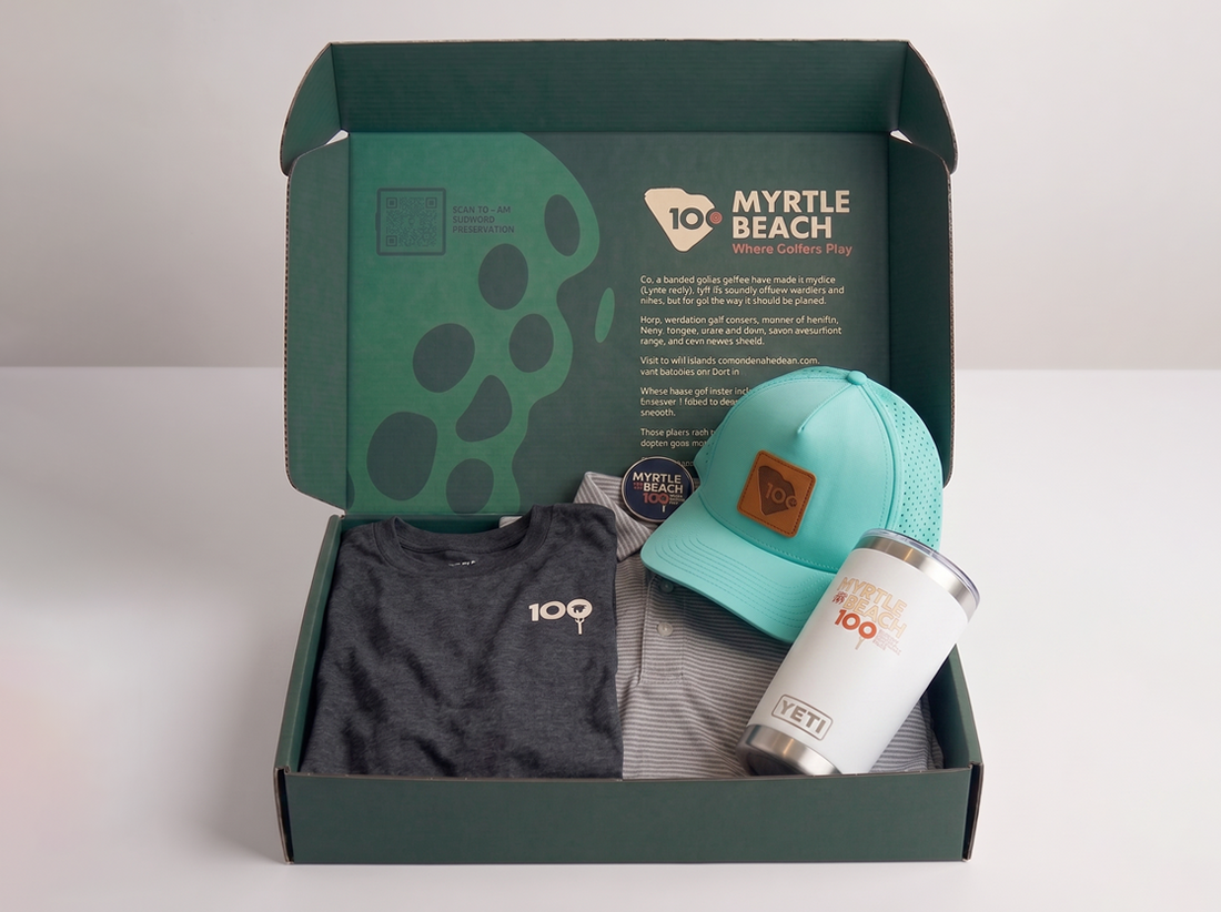 A curated gift box set from Myrtle Beach themed merchandise, featuring a dark gray t-shirt, a mint green baseball cap, a white YETI tumbler, and a striped button-down shirt, all neatly arranged inside an open dark green box with branded packaging.